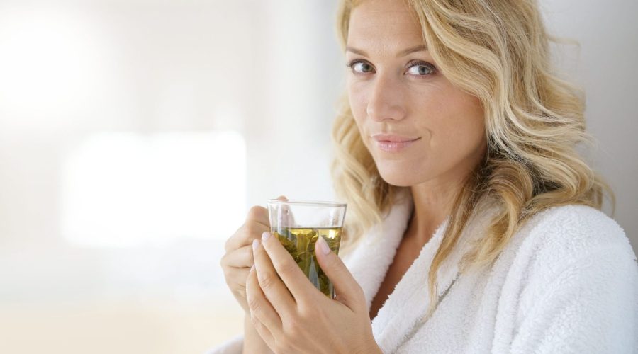 Portrait of attractive 40-year-old woman in bathrobe drinking infusion